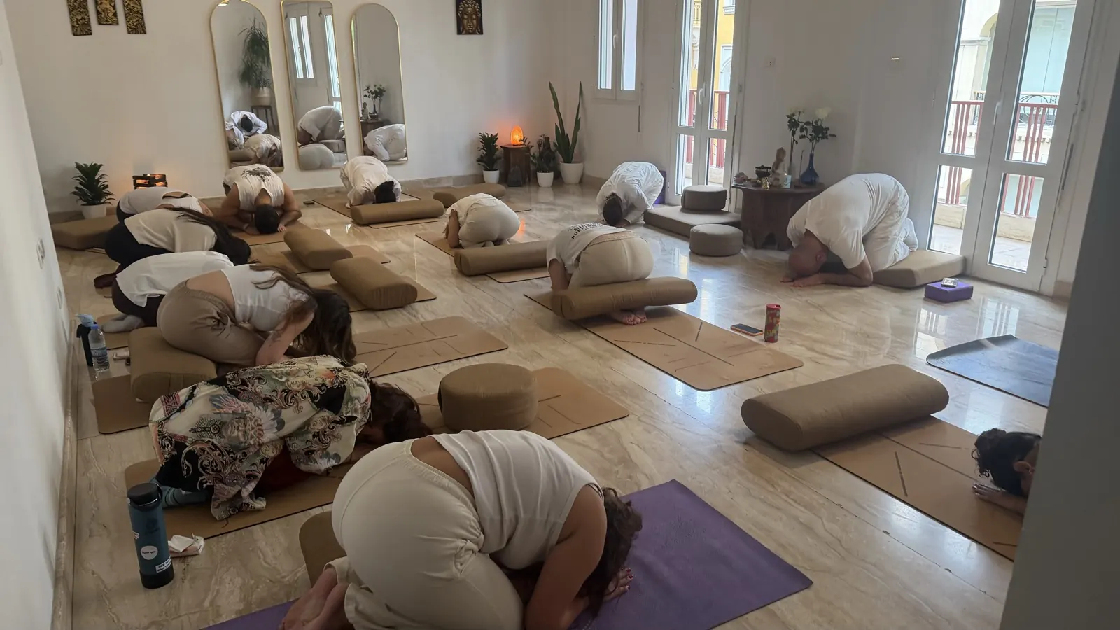Participants resting in child’s pose on mats and bolsters during the Vipassana event